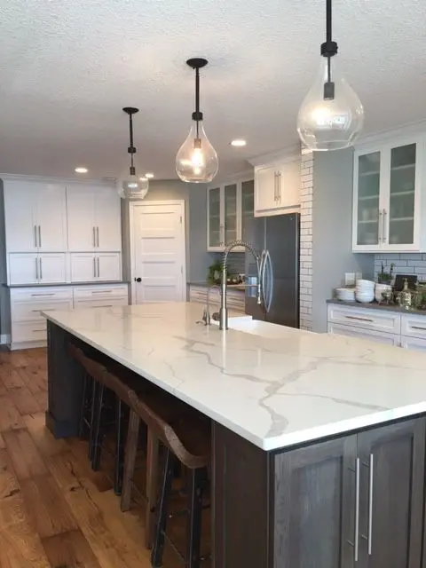 a statement kitchen island in dark wood with a white quartz counter can transform any kitchen
