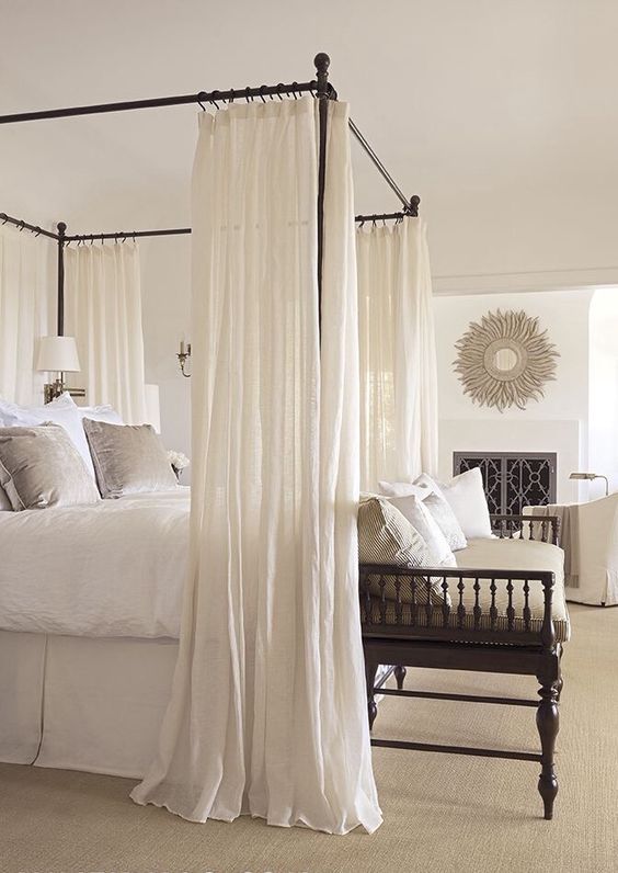 black frame canopy bed with airy white curtains for a dreamy feel