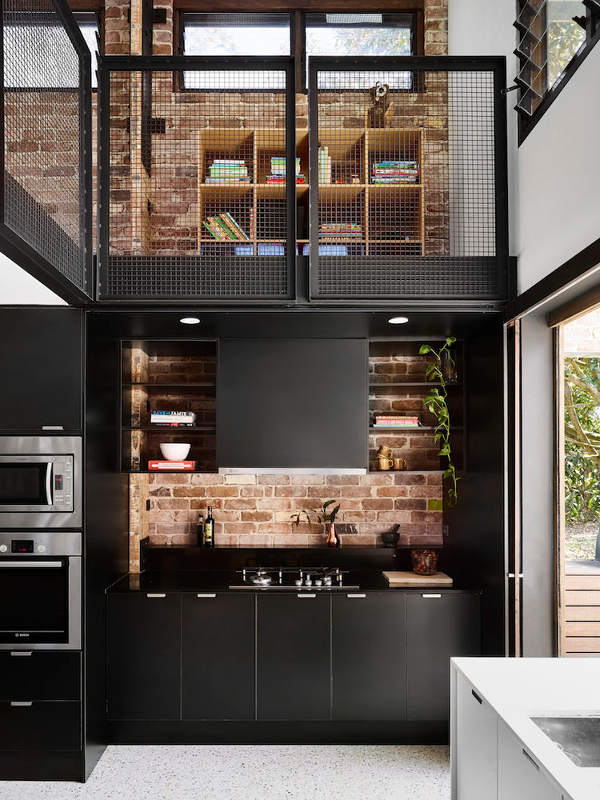 The brick backsplash creates a cool contrast with sleek black panels