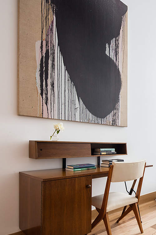 The home office nook features mid-century modern desk with sotrage and another eye-catchy work of art