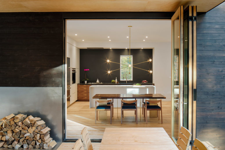 The kitchen is modern, black and white, with a waterfall kitchen island and a cool pendant lamp