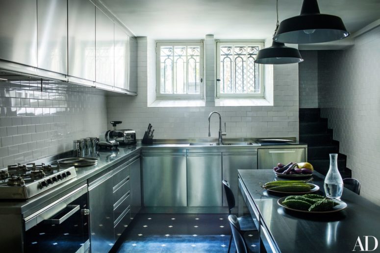 The kitchen is modern, with simple white tiles and stainless steel cabinets and appliances, the lamps are vintage ones
