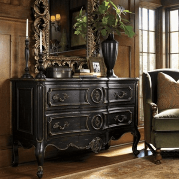 a dark wood sideboard with antique decor, a mirror and a dark vase