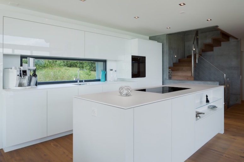 The kitchen is done in white, everything possible is hidden for a sleek look and there's a window instead of a backsplash