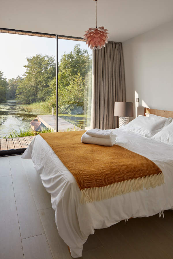 The master bedroom shows beautiful views of the lake and a cool cozy bed, nothing else needed