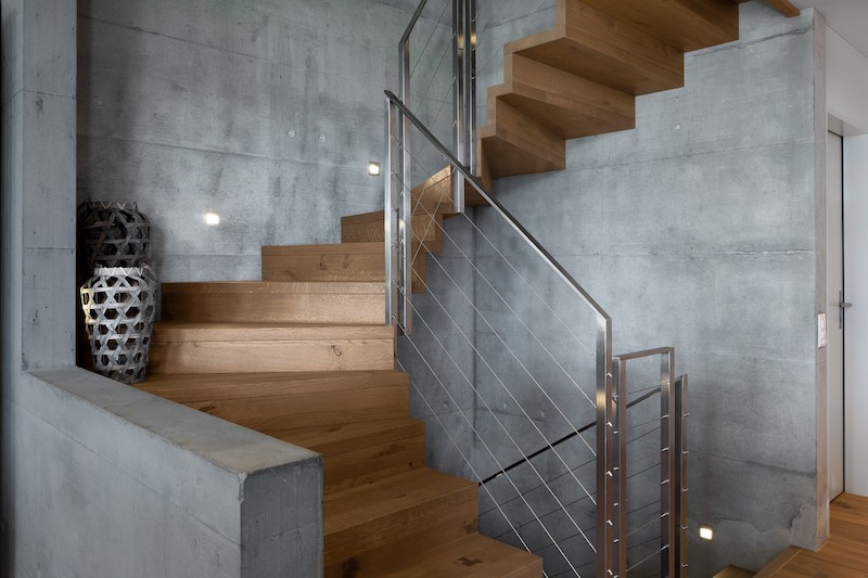 The spiral staircase has a very graceful and elegant design, featuring a combination of wood and concrete