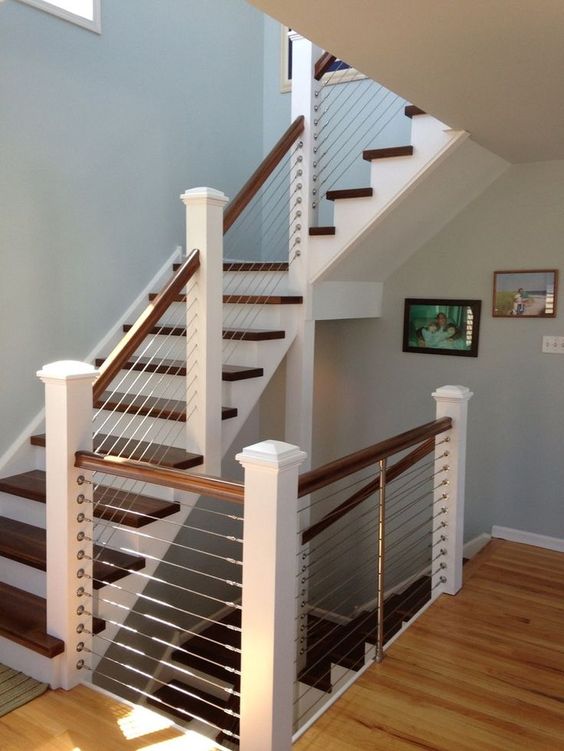 classic white and dark wood staircase is made more modern with cable railings