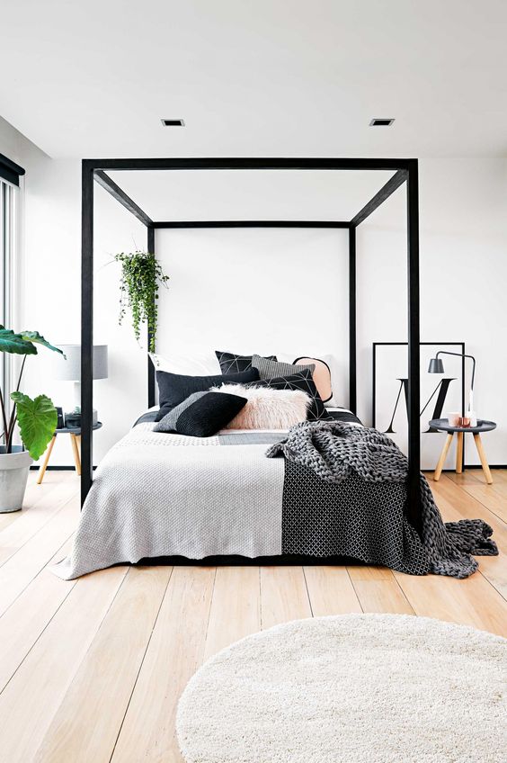chic modern bedroom with a black frame bed and lots of greenery