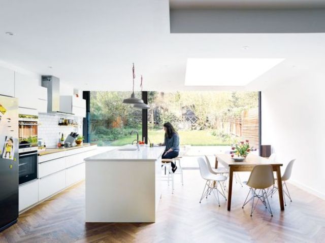Light filled kitchen in white with a large kitchen island and dinign area with mid century modern furniture