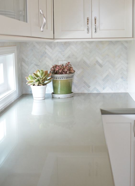 white cabinets with marble herringbone backsplash and sage green quartz countertops