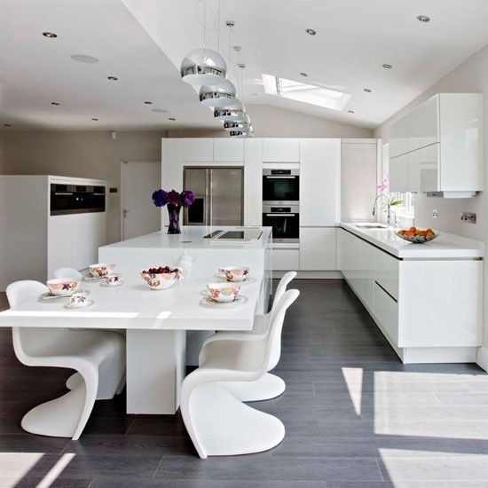 ultra-modern white kitchen and a corresponding dining space with sculptrual chairs