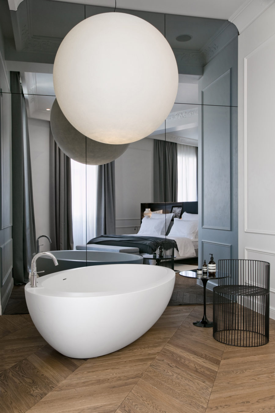 Modern mirror wall, a free standing bathtub and an oversized sphere lamp
