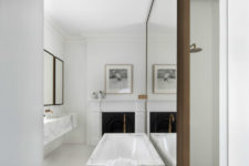 18 a marble bathtub in front of a mirror wall and mirrors on the opposite wall