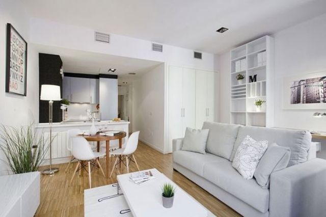 small space uniting a kitchen, a diner and a living room all decorated in modern style and off-whites