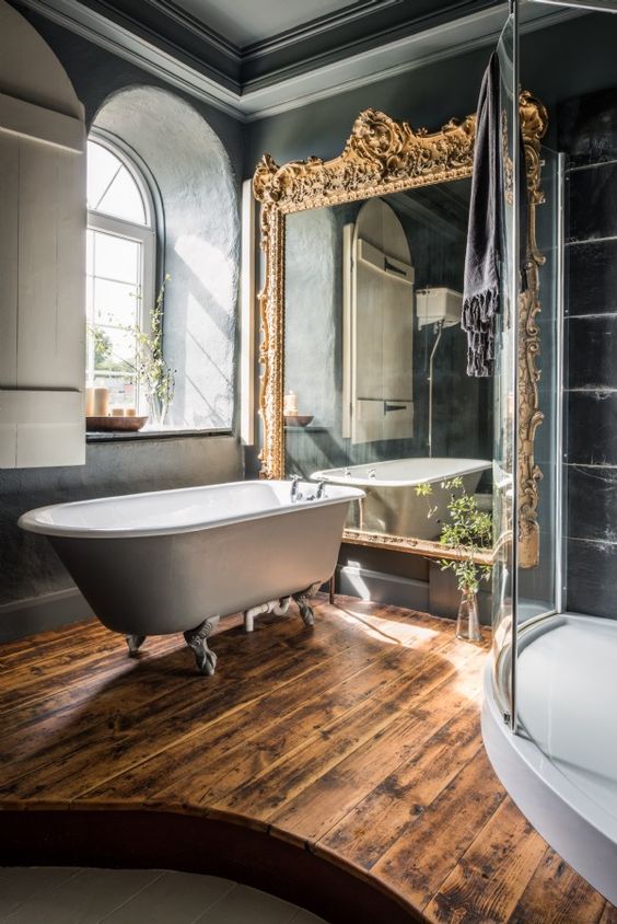 dark bathroom decor, a vintage free-standing bathtub and a large mirror in a refined gilded frame