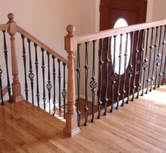 Chic light colored wooden staircase with dark wrought metal railing for a contrast
