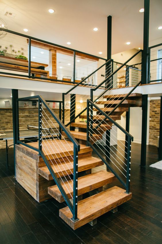 Ultra modern yet a bit rustic light colored reclaimed wood staircase with dark metal and cable railing