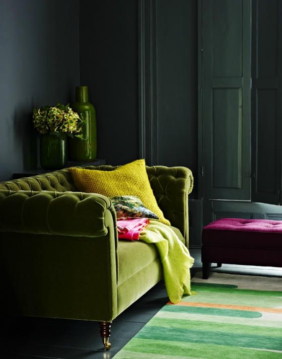 green plush sofa and bold yellow accents in a moody room