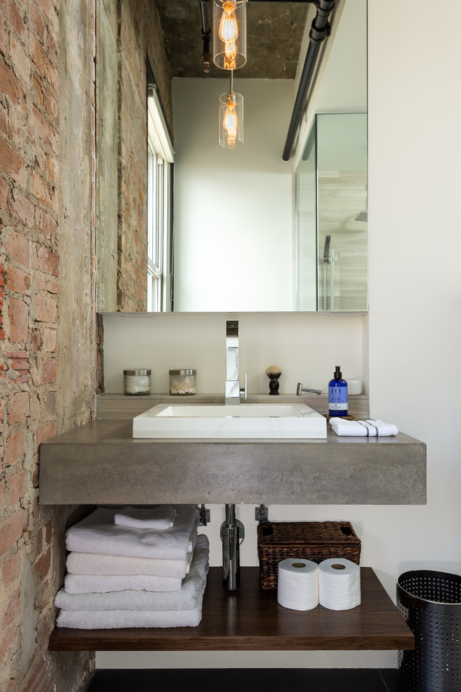 A minimalist concrete vanity looks great by an exposed brick wall. (CONTENT Architecture)