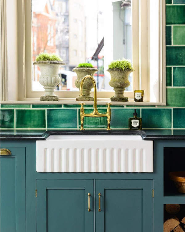 The blue cabinets with copepr handles look elegant and traditional, and stone urns are used instead of usual pots