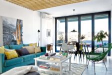 02 The living room features a turquoise sofa, wooden beams on the ceiling and walls, they make the room cozier