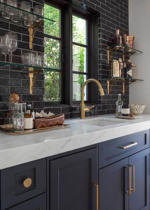 navy kitchen cabinets with brass handles and details with white stone countertops