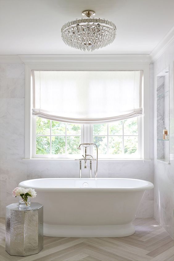 refined modern bathtub with a silver stool, Roman shades and a freestanding bathtub