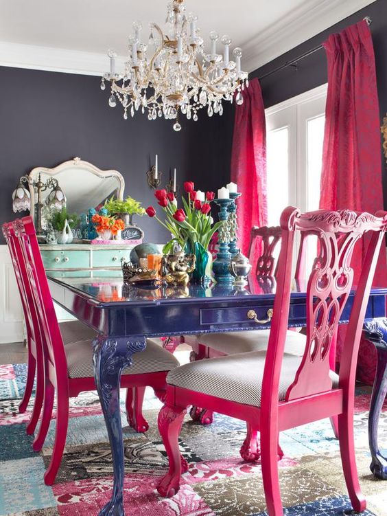a bold blue dining table, hot pink chairs and a crystal chandelier for a vibrant space