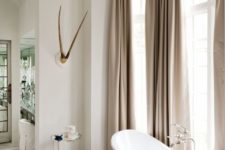 04 a feminine space with beige curtains, a pink stool and a refined oval bathtub on nickel legs