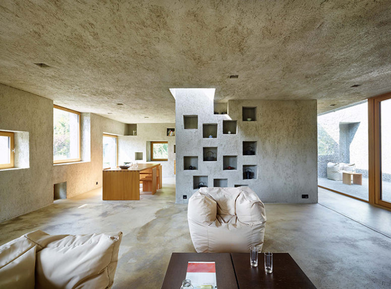 Concrete also dominates the interiors, it covers walls, floors and ceilings, and light-colored wood makes them cozier
