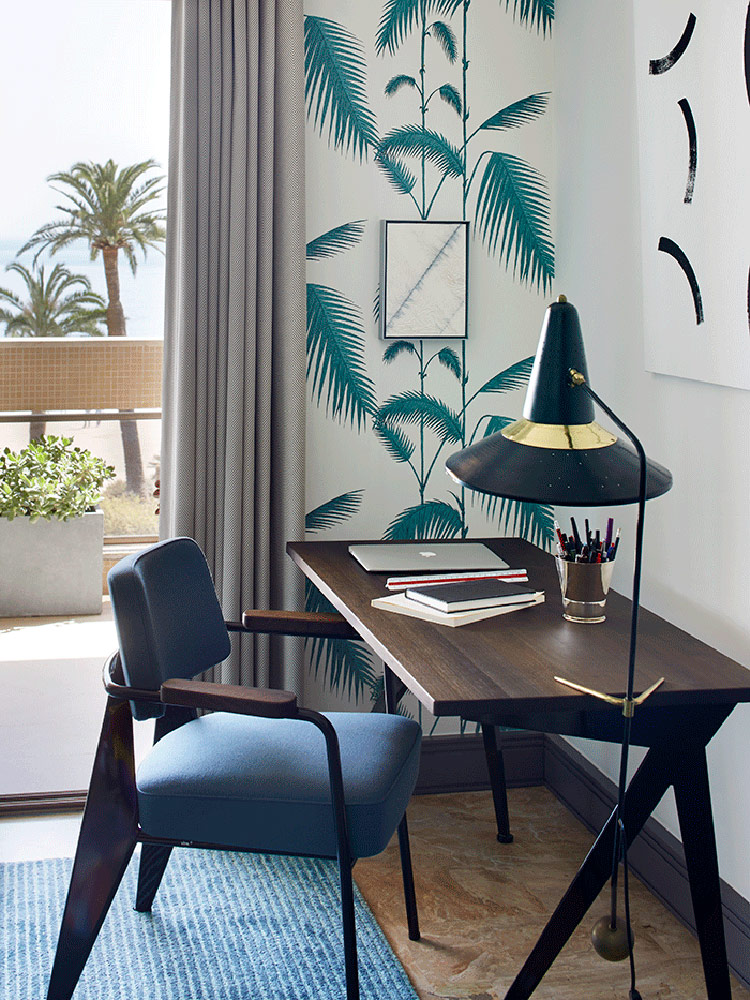 The home office nook features botanical print wallpaper and a withc hat inspired floor lamp
