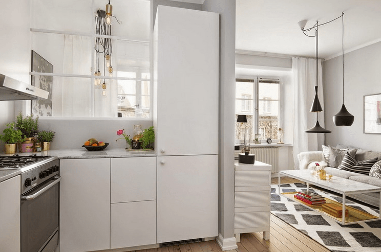 The kitchen is white with metallic accents and a false window going to the bedroom