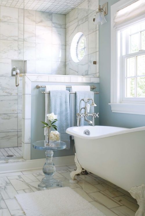 a light blue bathroom with a slip clawfoot tub with white legs