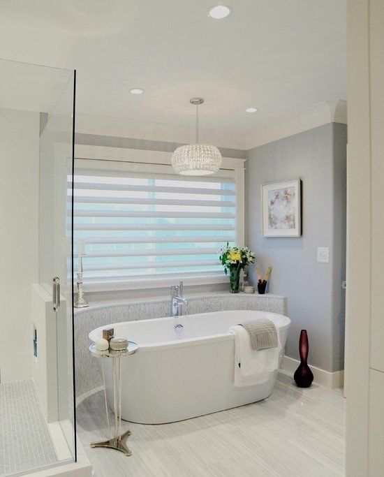 a modern freestanding bathtub in an alcove, a glam crystal chandelier and a metal stand