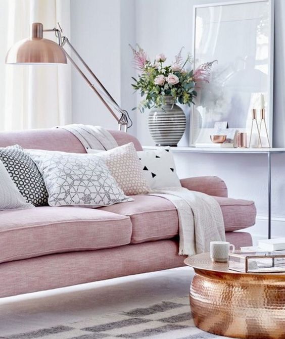 a pink upholstered sofa on tall legs looks cool with copper details