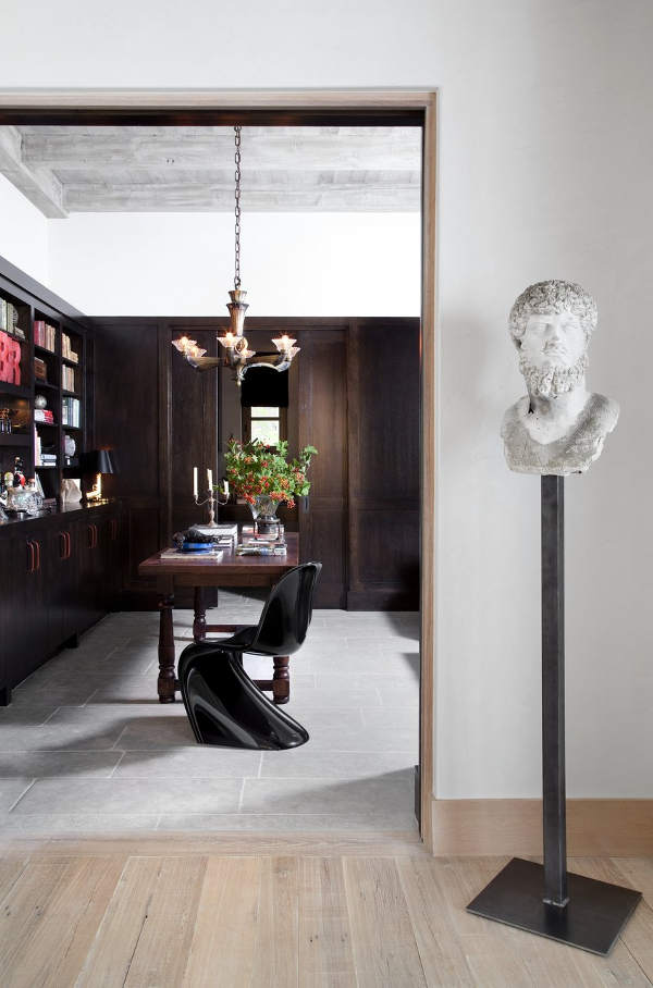 The home office is clad with dark wood, there are traditional shelves and a desk but a modern twisted chair