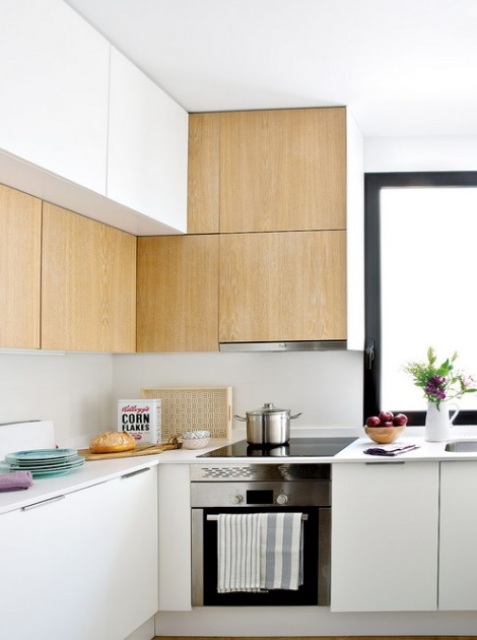 The kitchen has white and light colored wooden cabinets with no handles for a neat look