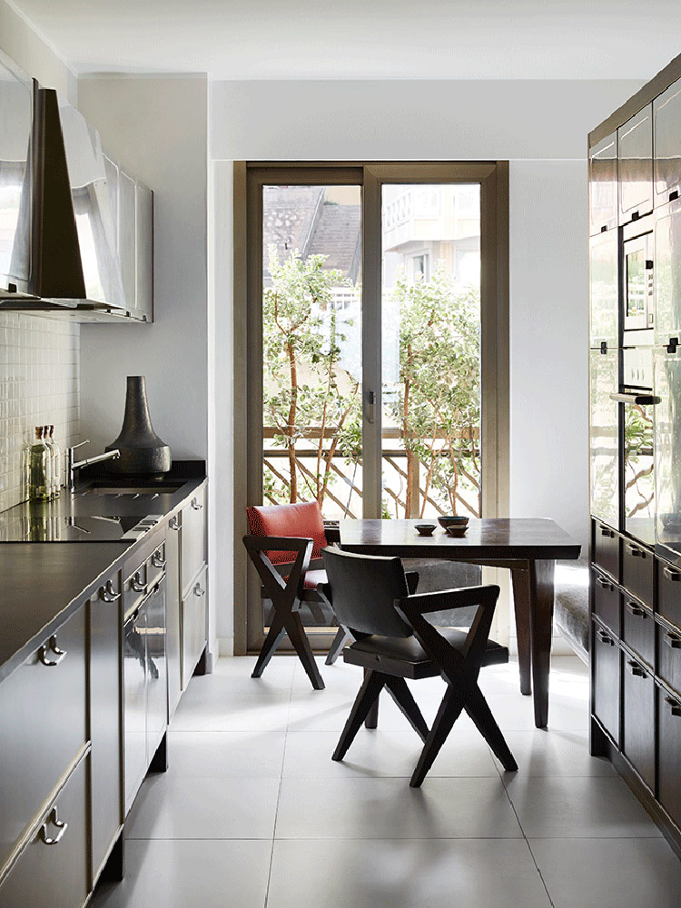 The kitchen is a dark mid-century modern one, with dark cabinets and a breakfast nook next to the glass door to the terrace