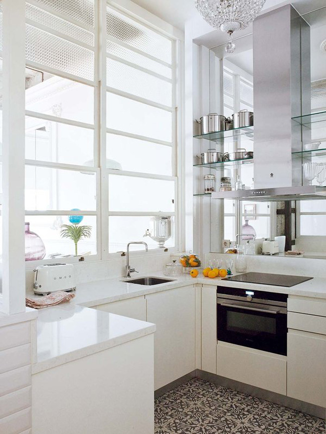 The kitchen is all white, it's modern and laconic, and a mirror wall make it look bigger