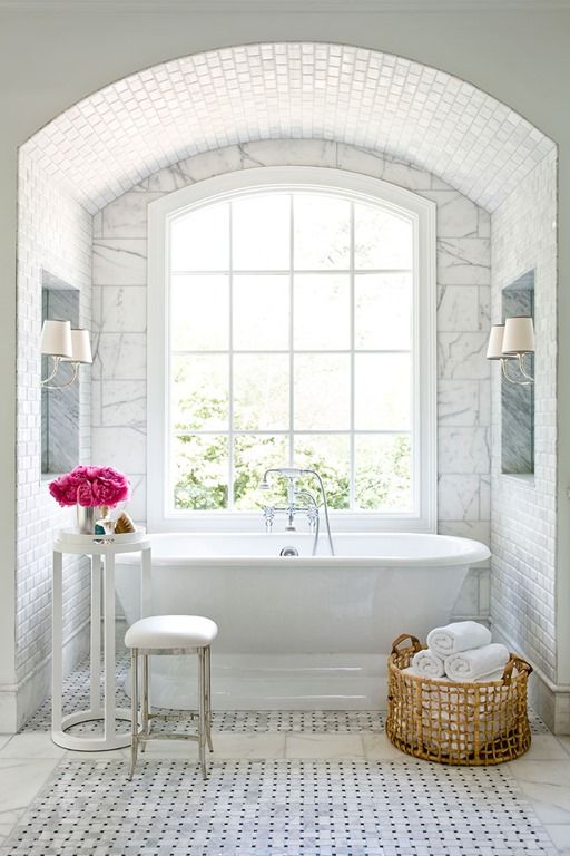 a glam bathtub niche with marble tiles, a flower stand and a large window for a cool view