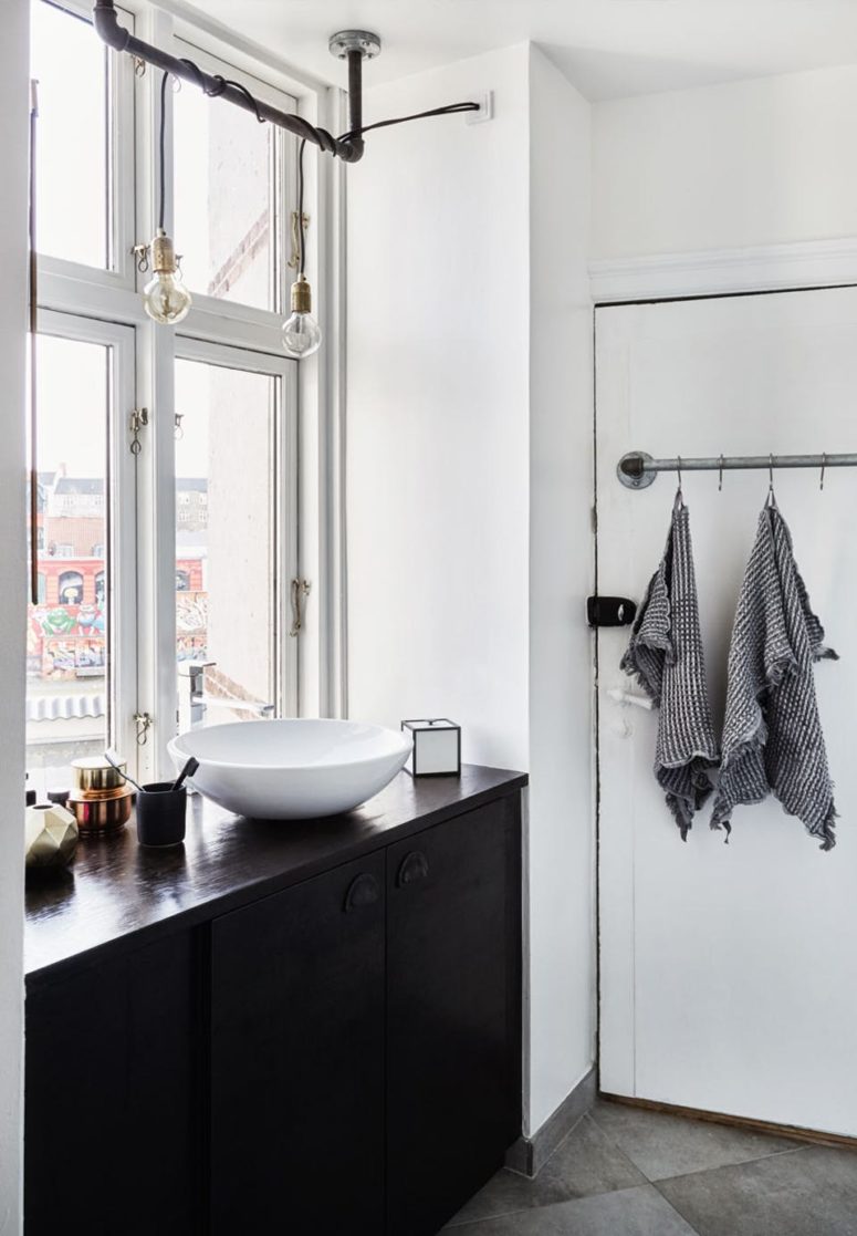 The bathroom shows black cabinets, and the sink is right next to the window to save the space and enjoy the view