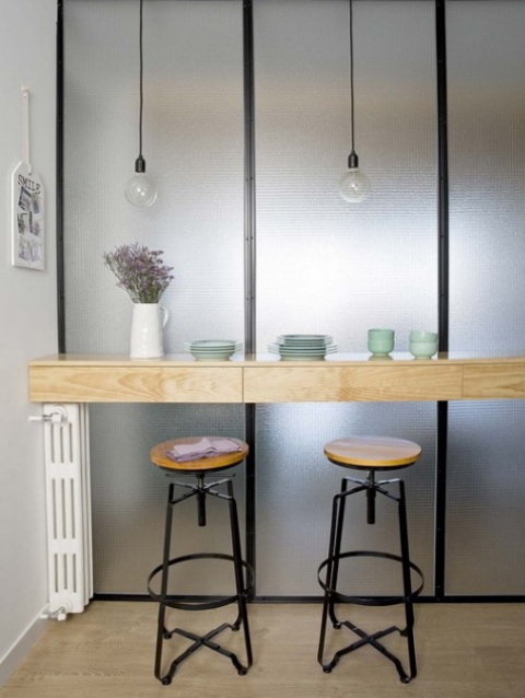 There's a breakfast nook with a wooden countertop and bulbs over the it for more light