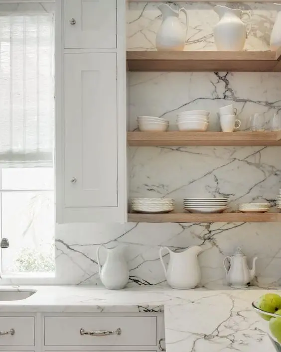 Stone slab counters and light colored wooden shelves for a modern fresh look