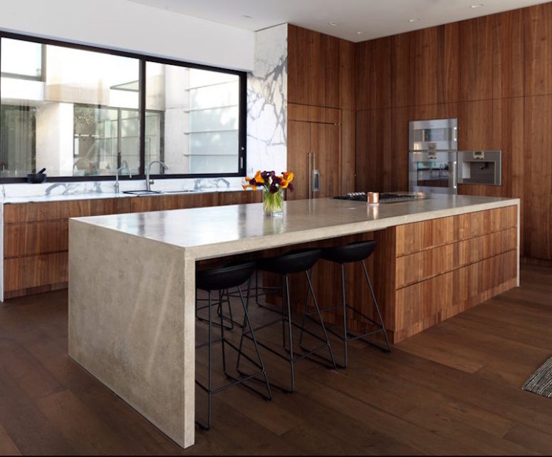 The kitchen is done in warm-colored wood, polished concrete and marble