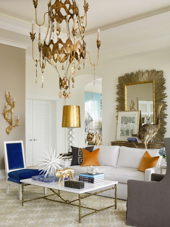 a whimsy living room with a chic brass chandelier and gold hanging details