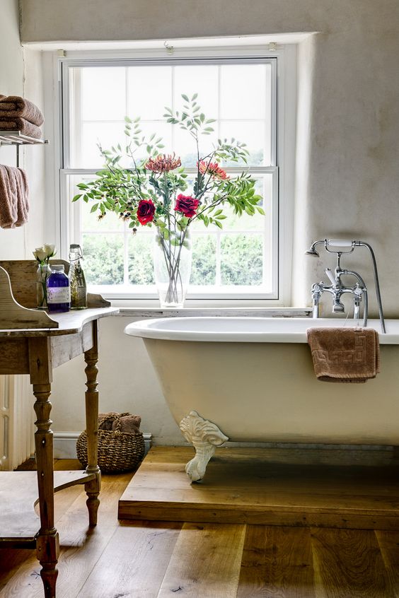 rustic bathroom with an ivory bathtub with white legs on a wooden stand