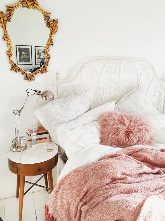 white metal bed with a curling headboard and pink bedding