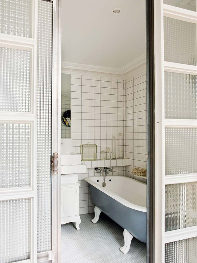 The bathroom features subway tiles, a free standing blue bathtub