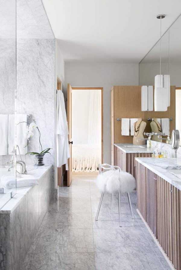 The master bathroom is clad with white marble and light-colored wood, I love glam accents