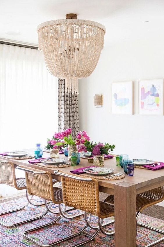 a modern boho dining space with wicker furniture and a large glam chandelier